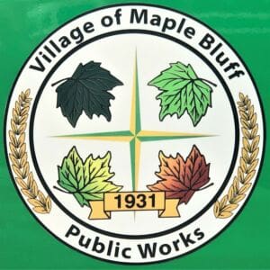 Seal for the Village of Maple Bluff Public Works, featuring four colored maple leaves, a gold compass star, and the year 1931, surrounded by laurel branches on a green background.