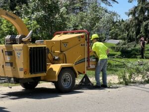 A man in a yellow shirt and helmet using a machine.